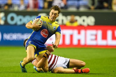 Matty Ashton #5 of Warrington Wolves is tackled by Jai Field #23 of Wigan Warriors