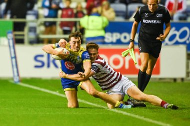Matty Ashton #5 of Warrington Wolves is tackled into touch by Sam Halsall #25 of Wigan Warriors 