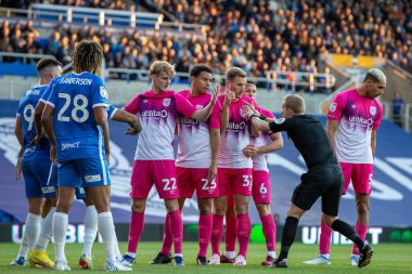 Referee Gavin Ward tells the Huddersfield Town players to stay where they are during the free kick 