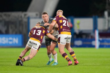Jordan Lane #13 of Hull FC is held by Luke Yates #13 and Oliver Wilson of Huddersfield Giants 