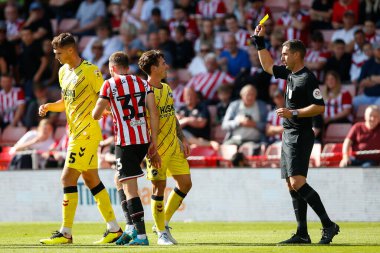 Referee David Coote issues a yellow card to both Rhys Norrington-Davies #33 of Sheffield United and Danny McNamara #2 of Millwall
