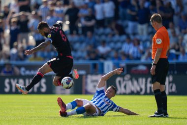 Jonathan Hogg #6 of Huddersfield Town slides in to tackle Lewis Baker #8 of Stoke City in front of Referee Maatthew Donohue 