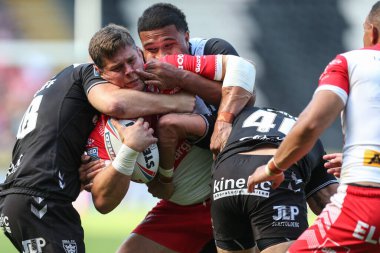 Louie McCarthy-Scarsbrook #15 of St Helens is tackled by Chris Satae #10 and Ellis Longstaff #38 of Hull FC