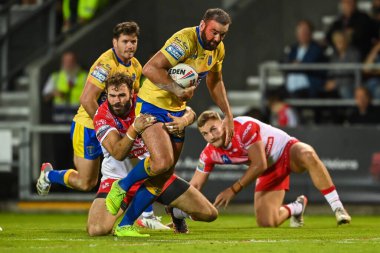 Kane Linnett #12 of Hull KR is tackled by Alex Walmsley #8 of St Helens