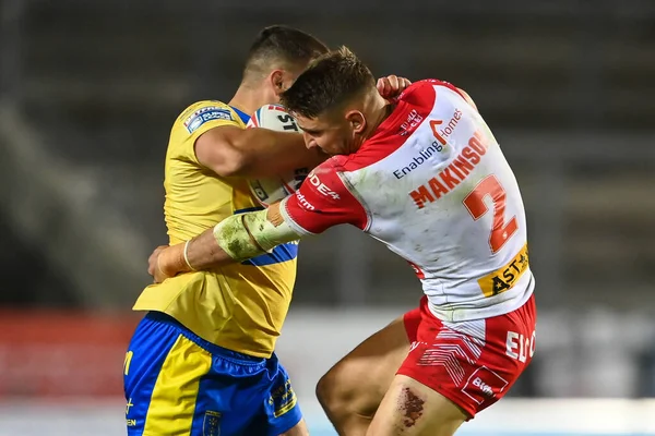 Matty Storton #13 of Hull KR is tackled by Tommy Makinson #2 of St Helens