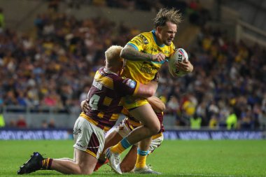 Blake Austin #6 of Leeds Rhinos is tackled by Matty English #14 of Huddersfield Giants 