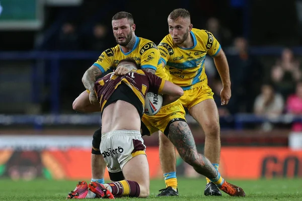 Oliver Russell #23 of Huddersfield Giants is tackled by Zak Hardaker #33 of Leeds Rhinos 