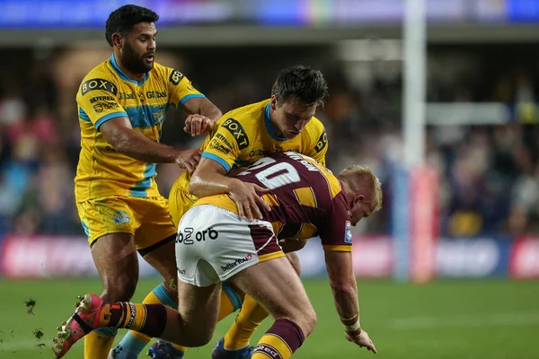 Oliver Wilson #20 of Huddersfield Giants is tackled by Tom Briscoe #20 of Leeds Rhinos 