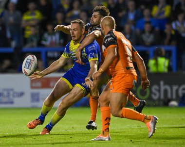 Ben Currie #11 of Warrington Wolves offloads the ball despite the tackle of Jake Mamo #4 of Castleford Tigers