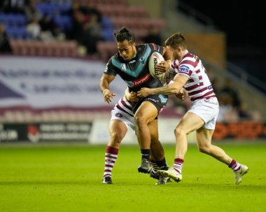 Agnatius Paasi #17 of St Helens   breaks thrpugh the tackle of John Bateman #13 of Wigan Warriors