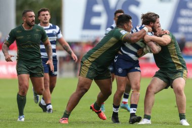 Joe Shorrocks #22 of Wigan Warriors is tackled by Albert Vete #8 and Zach Fishwick #34 of Hull KR 