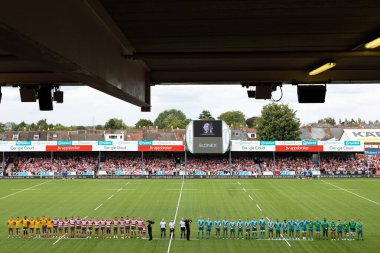 Oyuncular bir dakikalık saygı duruşunda sıralanırken, büyük ekranda İngiltere 'nin Gloucester Premiership maçı sırasında Gloucester vs Wasps' a karşı Kingsholm Stadyumu 'nda perşembe günü vefat eden Kraliçe II. Elizabeth' in görüntüsü görülüyor.