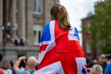 Büyük Britanya bayrağına sarılı genç bir kız, Birkenhead, Birkenhead, Birleşik Krallık 'ta Kral III. Charles Bildirgesi sırasında izliyor.