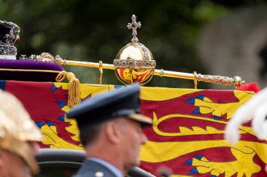 Kraliyet Krallığı Kraliyet Standardı 'na dayanır. Kraliçe Elizabeth 11' in tabutunun üzerinde Orb ve Asa vardır. Cenaze alayının ardından Westminster Manastırı 'nda, Londra Şehir Merkezi' nde, Birleşik Krallık 'ta. 