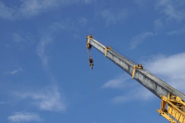 Yellow Telescopic Arm of a Mobile Crane Operating at a Construction Site with Blue Sky Background