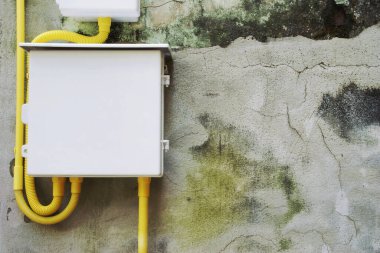 Electrical Panel with Yellow Flexible Conduit Wiring on Old Damaged Cement Plaster Wall