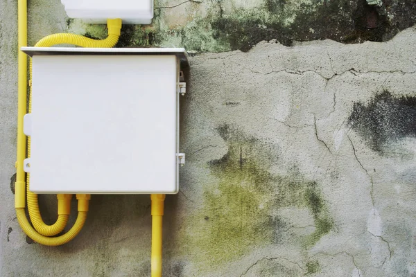 Electrical Panel with Yellow Flexible Conduit Wiring on Old Damaged Cement Plaster Wall