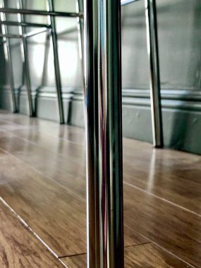 Kapalı, parlak metal bar taburesi bacakları ve ahşap zemin.