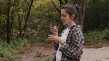 Yaz ormanındaki güzel kız çay içiyor ve yaz ormanlarındaki güzel kız çay içiyor ve doğanın tadını çıkarıyor.