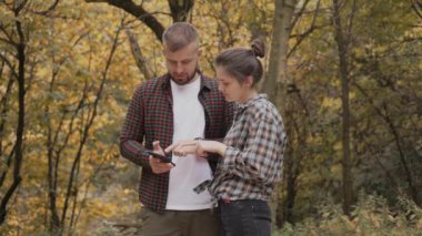 Sonbahar ormanında aşık genç bir çift doğanın tadını çıkarıyor ve telefona bakıyor.
