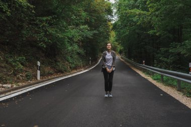 Güzel kız yol kenarındaki ormanda yürüyor.