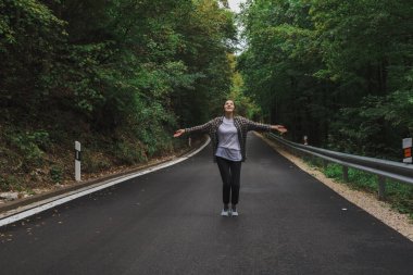 Güzel kız yol kenarındaki ormanda yürüyor.