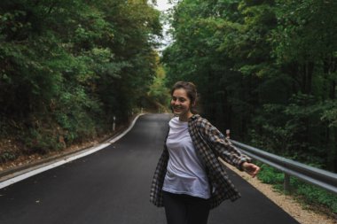 Güzel kız yol kenarındaki ormanda yürüyor.