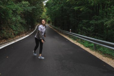 Güzel kız yol kenarındaki ormanda yürüyor.
