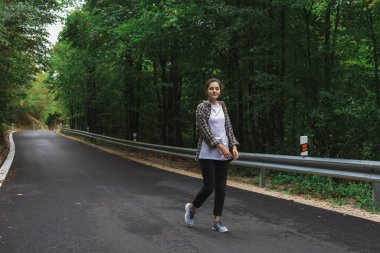 Güzel kız yol kenarındaki ormanda yürüyor.