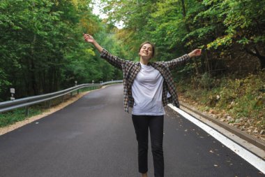 Güzel kız yol kenarındaki ormanda yürüyor.