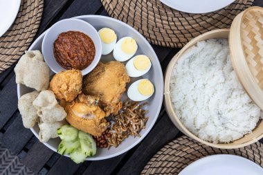 Nasi lemak kızarmış tavuk, ançüez, yumurta, yer fıstığı ve sambal ile popüler Malezya lezzeti, hindistan cevizi sütünde pilav ile servis edilir.