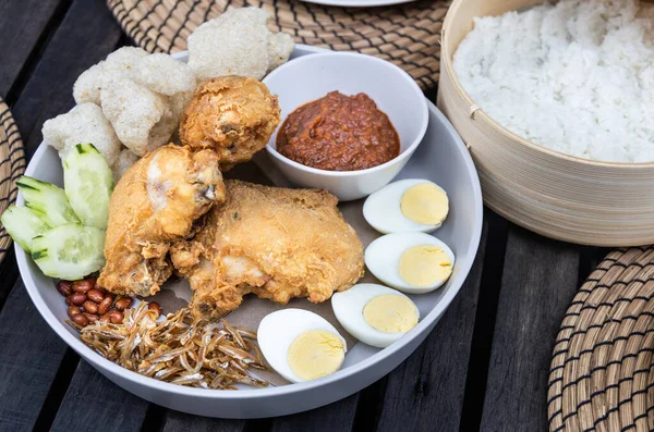 Nasi lemak kızarmış tavuk, ançüez, yumurta, yer fıstığı ve sambal ile popüler Malezya lezzeti, hindistan cevizi sütünde pilav ile servis edilir.