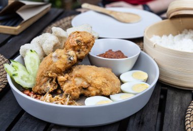 Nasi lemak kızarmış tavuk, ançüez, yumurta, yer fıstığı ve sambal ile popüler Malezya lezzeti, hindistan cevizi sütünde pilav ile servis edilir.