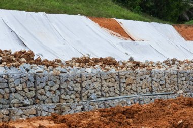 Series of close-up slope retention construction design with rocks and mesh to manage landslide in residential area clipart