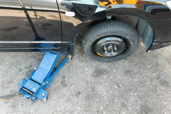 道路側で一時緊急交換タイヤにパンクタイヤを交換するための油圧自動車ジャッキリフト車 — ストック写真