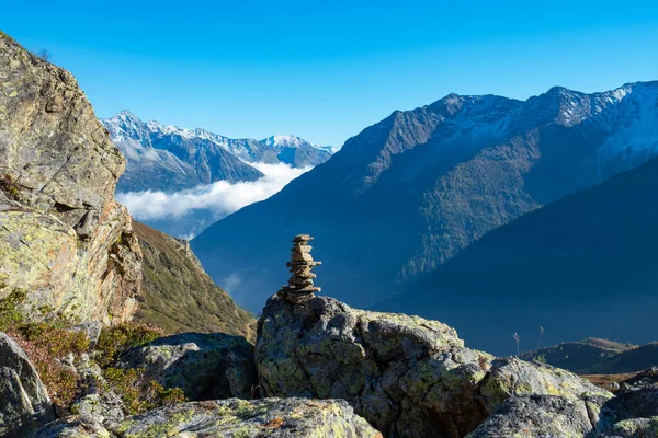 Senderismo en Suiza Central. Un cairn marcando un sendero, altas montañas en el fondo —  Fotos de Stock