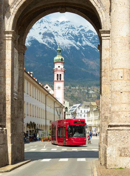 Innsbruck, Austria - April 17th 2018: View through a portal into the city centre with a tram passing historic buildings — Stock Fotó