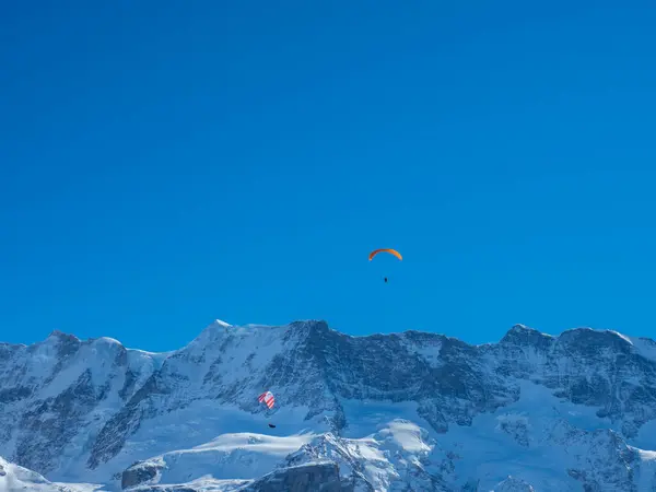 Två skärmflygning framför en snötäckt bergsrygg i Schweiz — Stockfoto