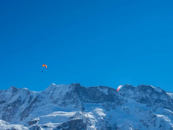 瑞士，两名滑翔伞运动员在雪地覆盖的山脊前 — 图库照片