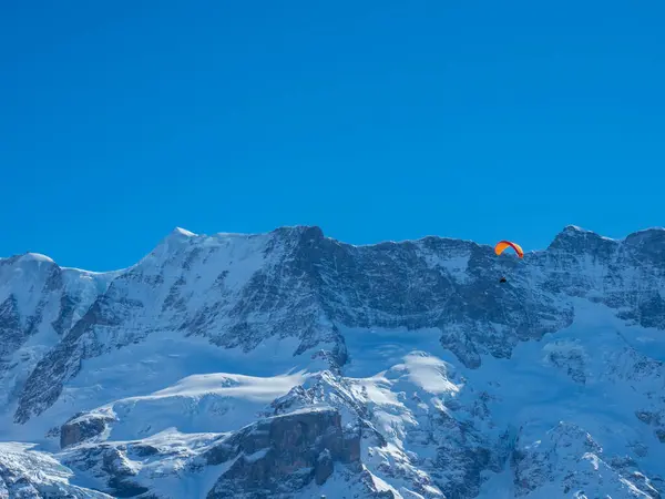 Paraglider před zasněženým horským hřebenem ve Švýcarsku — Stock fotografie
