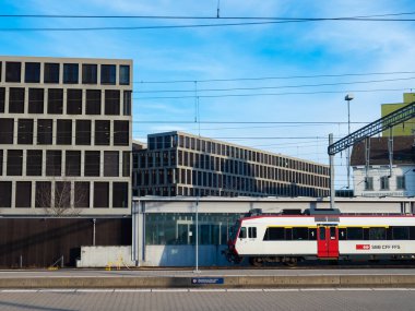 Brugg AG, İsviçre - 13 Mart 2022: Modern iş binalarıyla çevrili demiryolu istasyonu