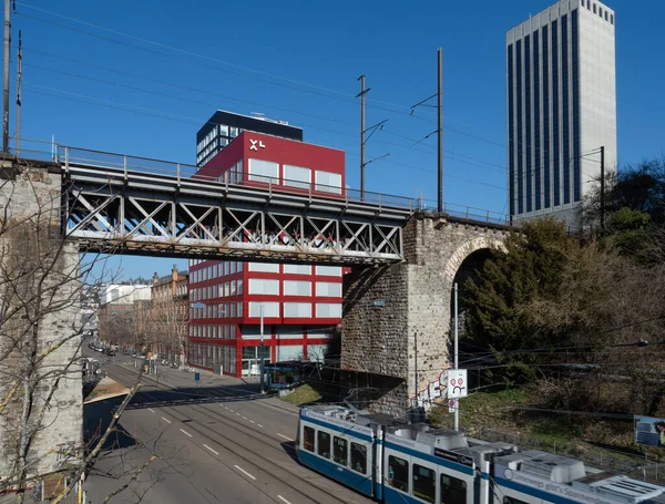 Zurich, Switzerland - March 5th 2022: A Tram train crossing below a railway bridge in a business district — Foto de Stock