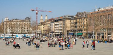 İsviçre 'nin Zürih kentinin ana meydanlarından Sechselat. platz' da bahar güneşinin tadını çıkaran insanlar. Meydanı çevreleyen tarihi binalar.