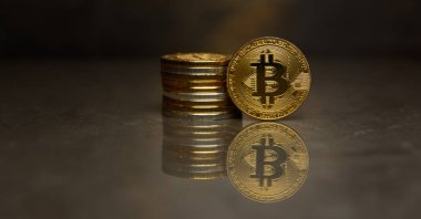  yansıtıcı yüzeyde altın bitcoin ve sikke yığını