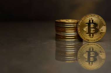  yansıtıcı yüzeyde altın bitcoin ve sikke yığını