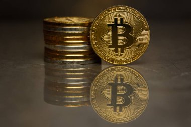  yansıtıcı yüzeyde altın bitcoin ve sikke yığını