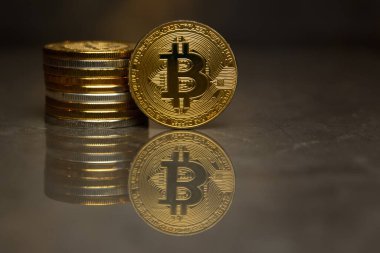  yansıtıcı yüzeyde altın bitcoin ve sikke yığını