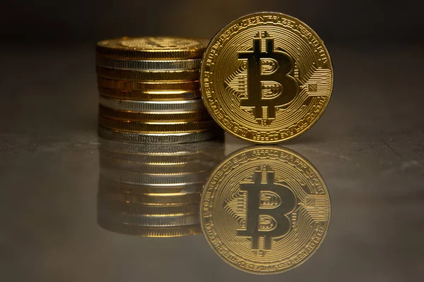  yansıtıcı yüzeyde altın bitcoin ve sikke yığını