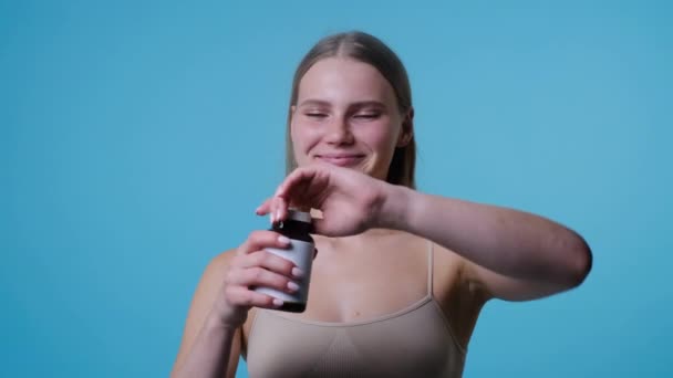 Young woman with bottle of pills taking pill — Stock Video