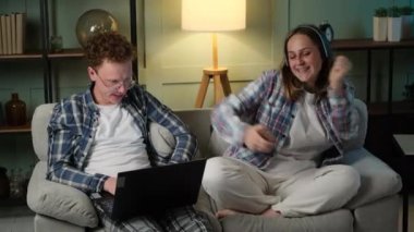 Dizüstü bilgisayarda çalışan serbest çalışan adam ve müzik dinleyen kadın.